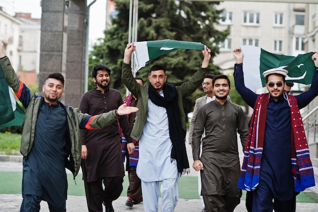 Grupo de hombres paquistaníes vestidos con ropa tradicional salwar kameez o kurta con banderas de Pakistán