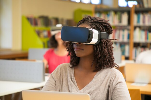Grupo interracial de estudiantes que utilizan la experiencia de realidad virtual para trabajar