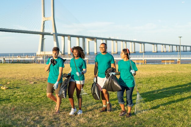 Grupo interracial de voluntarios llevando basura del césped de la ciudad