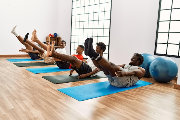 Grupo de jóvenes afroamericanos entrenando yoga en el centro deportivo