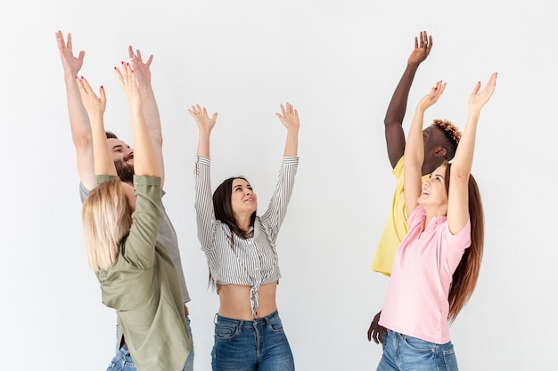 Grupo de jóvenes amigos con las manos levantadas arriba