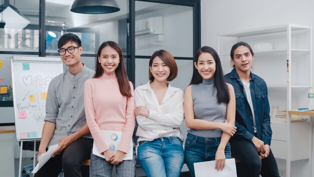 Grupo de jóvenes creativos de Asia en ropa casual elegante mirando a la cámara y sonriendo