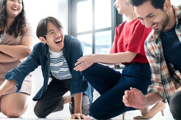Grupo de jóvenes creativos asiáticos y caucásicos felices disfrutan reír sonrisa y gran éxito emoción trabajo en equipo personas emprendedor de inicio de negocios casual lluvia de ideas reunión de negocios fondo de oficina