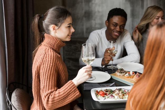 Foto gratuita grupo de jóvenes disfrutando de una cena y vino.