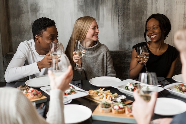 Grupo de jóvenes disfrutando de la comida y el vino.