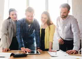 Foto gratuita grupo de jóvenes empresarios mirando tableta digital en el escritorio en la oficina