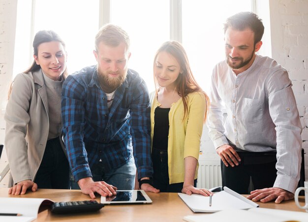 Grupo de jóvenes empresarios mirando tableta digital en el escritorio en la oficina