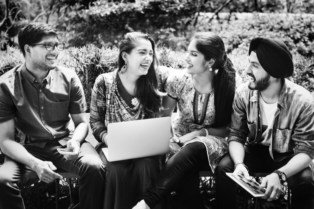 Grupo de jóvenes felices adultos indios usando la computadora portátil