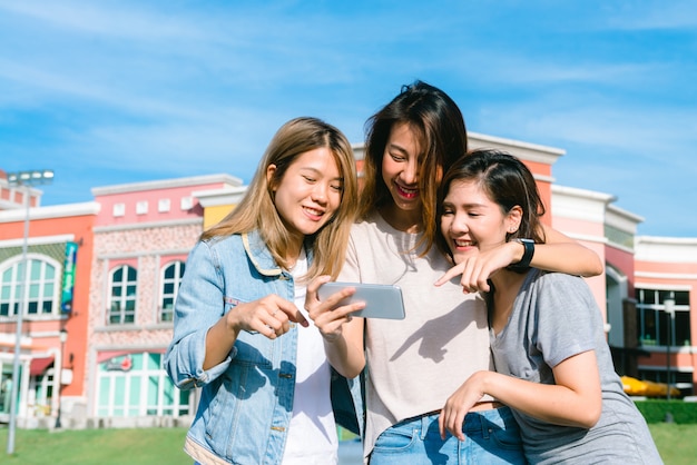 Grupo de jóvenes mujeres asiáticas se hacen un selfie con un teléfono en una ciudad en colores pastel después de ir de compras