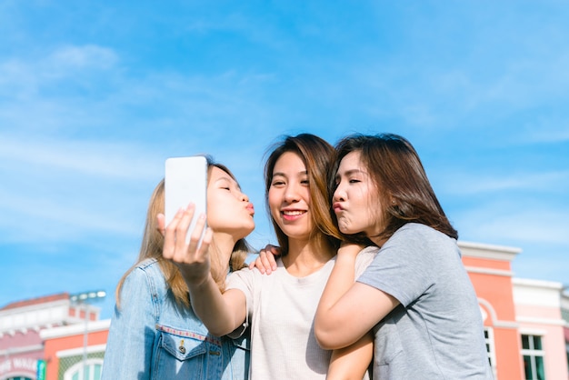 Grupo de jóvenes mujeres asiáticas se hacen un selfie con un teléfono en una ciudad en colores pastel después de ir de compras
