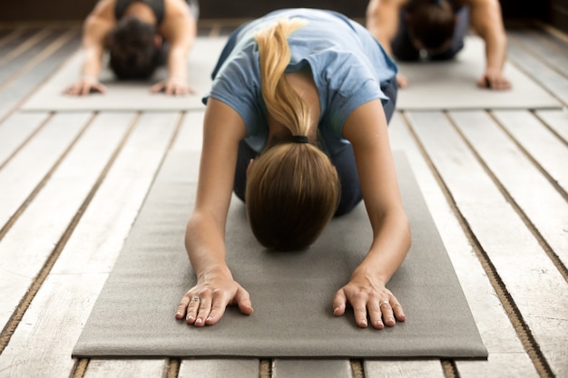 Grupo de jóvenes en pose balasana.