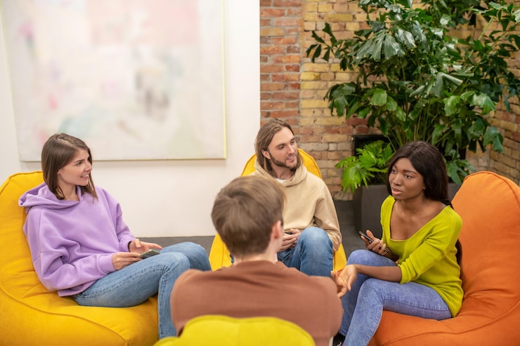 Foto gratuito un grupo de jóvenes sentados juntos y discutiendo algo.