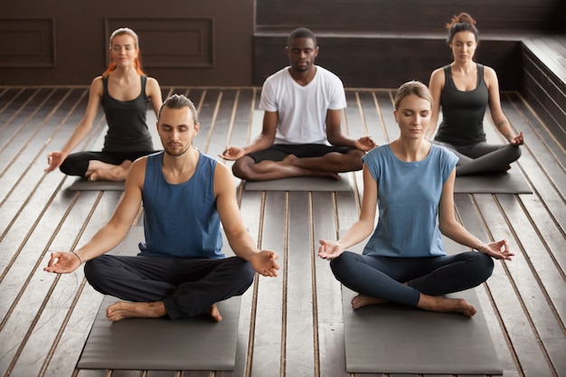 Grupo de jóvenes yoguis sentados en el ejercicio de Sukhasana