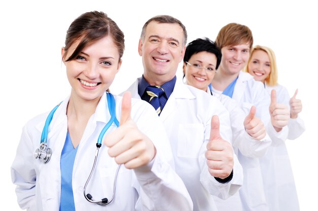 Grupo de médicos felices riendo con gesto pulgar hacia arriba de pie en línea