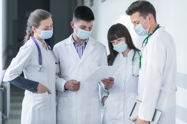 Grupo de médicos en máscaras leyendo papel