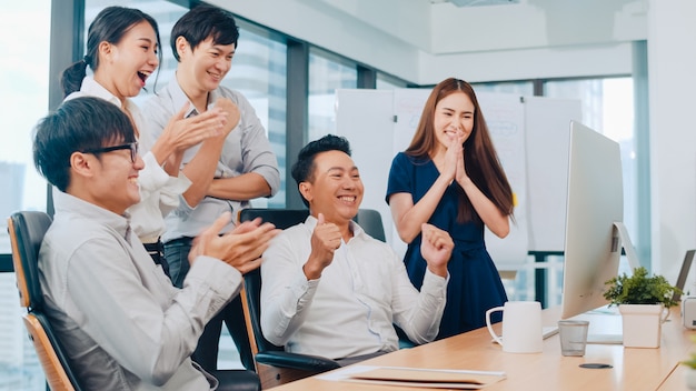 Grupo milenario de jóvenes empresarios Asia empresario y empresaria celebran dando cinco después de tratar de sentirse feliz y firmar un contrato o acuerdo en la sala de reuniones en la pequeña oficina moderna.