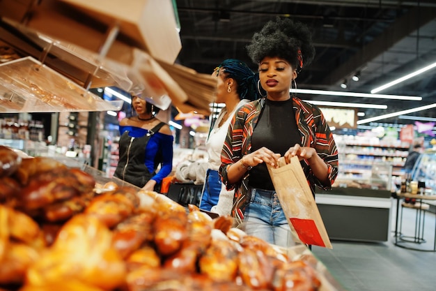 Foto gratuita grupo de mujeres africanas con carritos de compras cerca de productos horneados en un supermercado