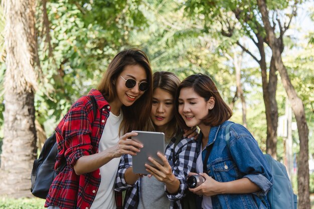Grupo de mujeres asiáticas que usan la cámara para tomar fotos mientras viajan en el parque en una ciudad urbana en Bangkok