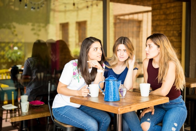 Grupo de mujeres bonitas sentadas juntas en un restaurante y cotilleando