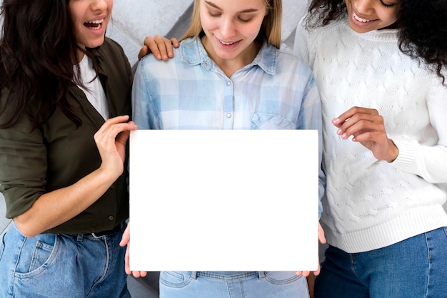 Foto gratuita grupo de mujeres jóvenes con un cartel vacío