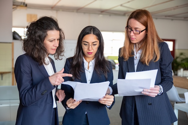 Grupo de mujeres jóvenes enfocadas que estudian un nuevo proyecto