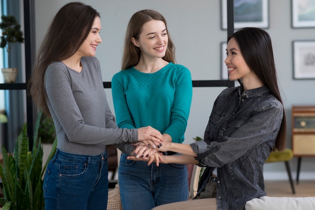 Grupo de mujeres jóvenes positivas tomados de la mano