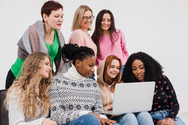 Grupo de mujeres mirando a través de una computadora portátil juntos