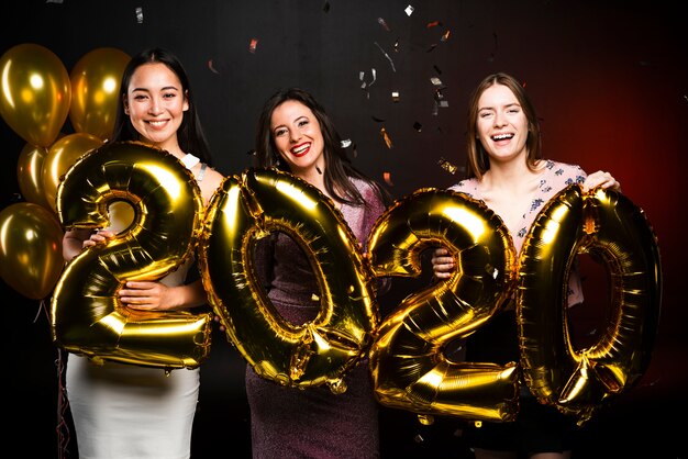 Grupo de mujeres posando con globos dorados en fiesta de año nuevo