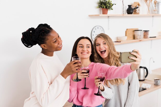 Grupo de mujeres tomando una selfie con una copa de vino