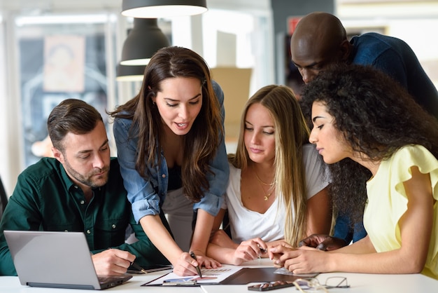 Grupo multiétnico de hombres jóvenes y de mujeres que estudian adentro.