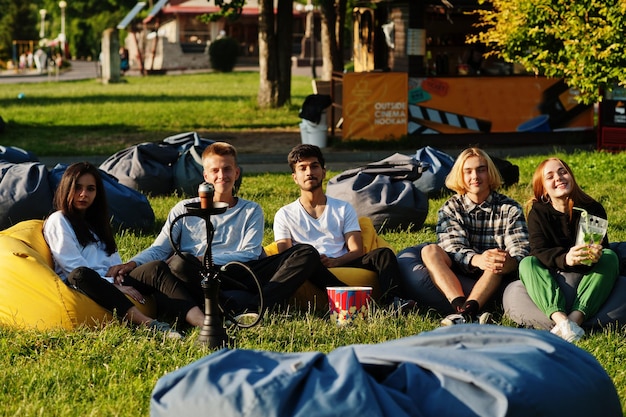 Grupo multiétnico joven de personas viendo películas en poof en cine al aire libre