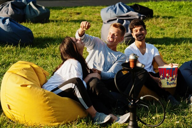 Grupo multiétnico joven de personas viendo películas en poof en cine al aire libre