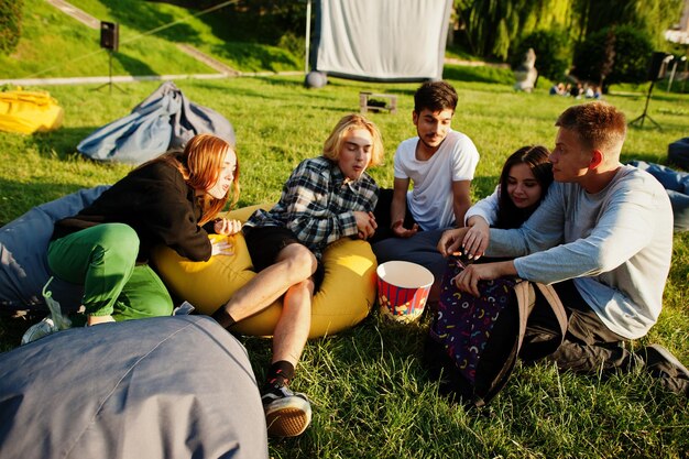 Grupo multiétnico joven de personas viendo películas en poof en cine al aire libre