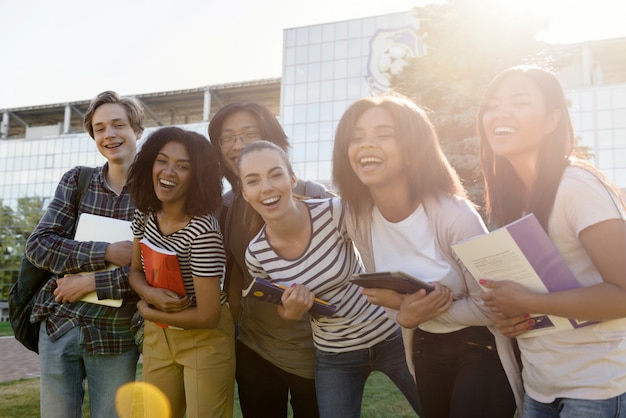 Grupo multiétnico de jóvenes estudiantes alegres de pie al aire libre