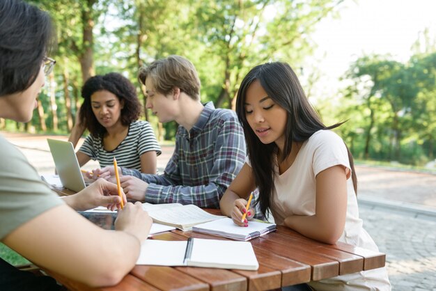 Grupo multiétnico de jóvenes estudiantes sentados y estudiando