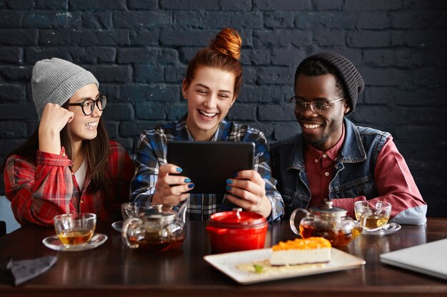 Grupo multiétnico de tres jóvenes disfrutando de la comunicación online