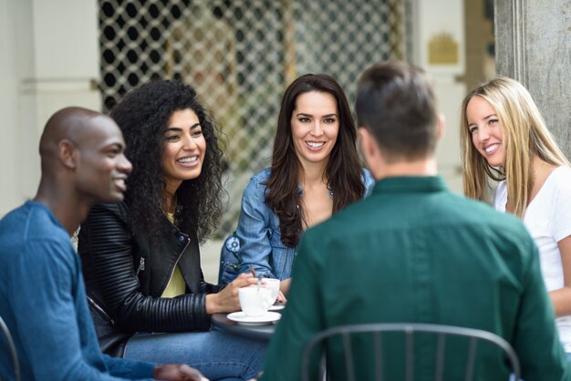 Grupo multiracial de cinco amigos que toman un café junto