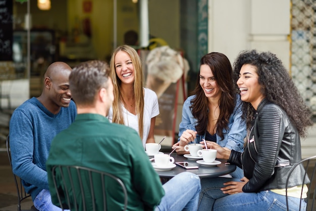 Grupo multiracial de cinco amigos que toman un café junto