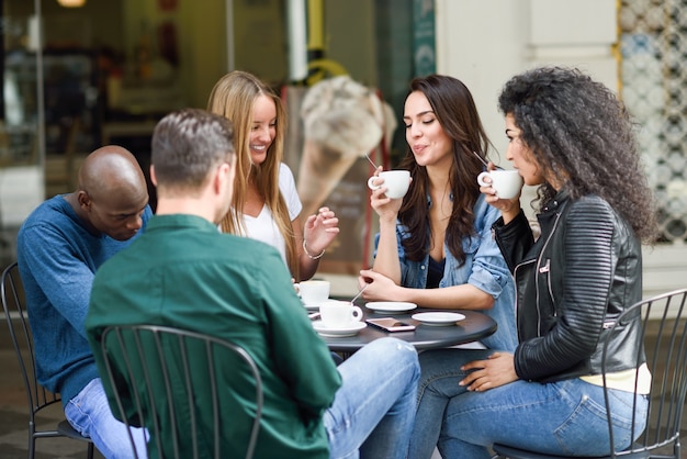 Grupo multiracial de cinco amigos que toman un café junto