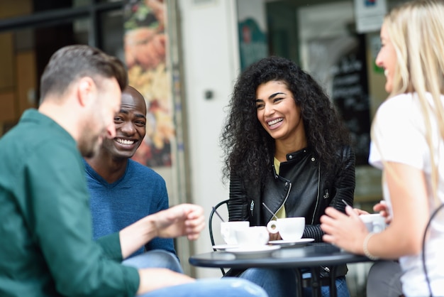 Grupo multiracial de cuatro amigos que toman un café junto