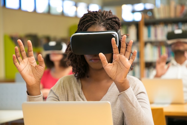 Grupo multirracial de estudiantes que usan dispositivos de realidad virtual durante la clase