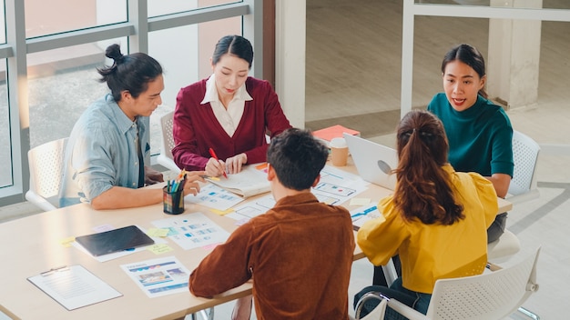 Grupo multirracial de jóvenes creativos en ropa casual elegante discutiendo ideas de negocios reunión proyecto de diseño de software de aplicaciones móviles en la oficina moderna. Concepto de trabajo en equipo de compañero de trabajo.