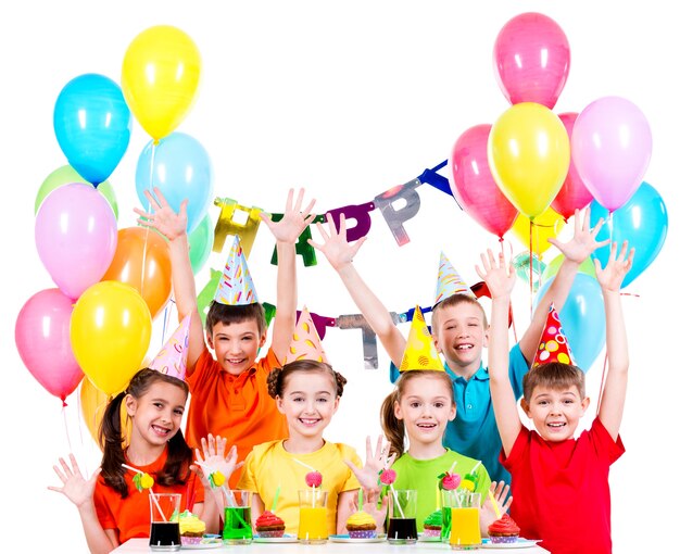 Grupo de niños con camisetas de colores en la fiesta de cumpleaños con las manos levantadas, aisladas en blanco.