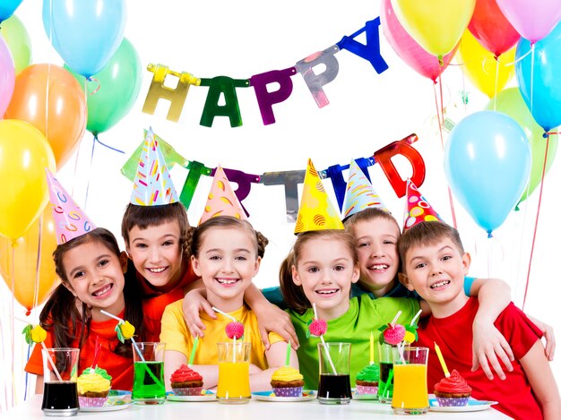 Grupo de niños felices en camisetas de colores que se divierten en la fiesta de cumpleaños - aislado en un blanco