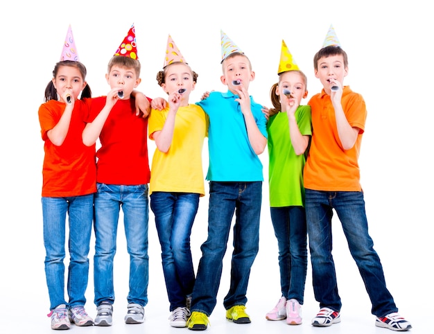 Grupo de niños felices en camisetas de colores con sopladores de fiesta - aislado en un fondo blanco.