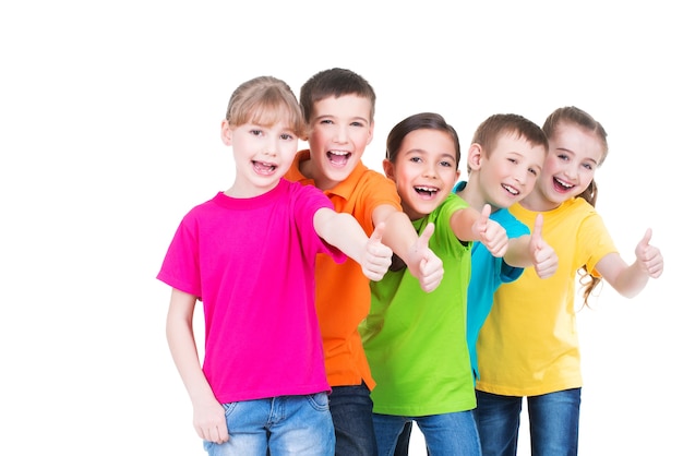 Grupo de niños felices con el pulgar hacia arriba firmar en coloridas camisetas de pie juntos, aislados en blanco.