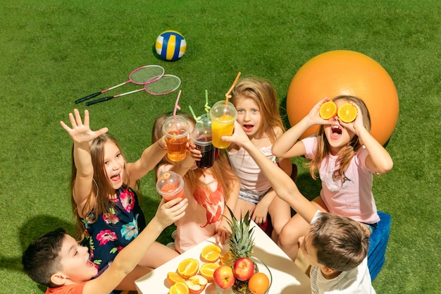 Foto gratuita el grupo de niños y niñas adolescentes sentados sobre la hierba verde en el parque