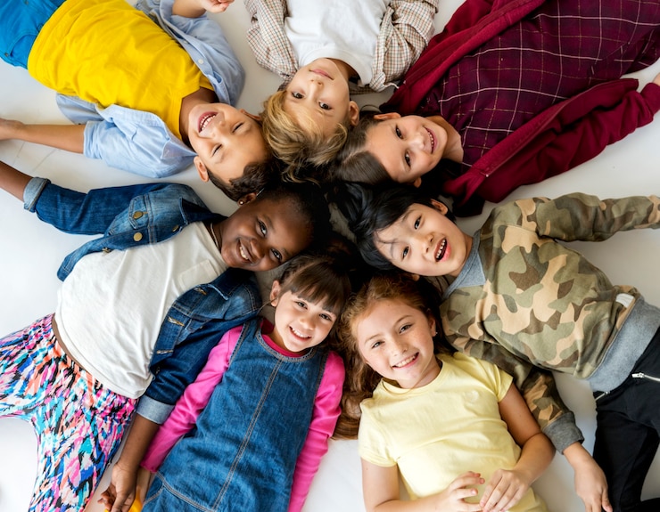 Foto gratuito un grupo de niños de primaria tumbados en el suelo y sonriendo