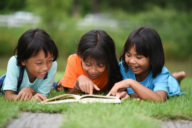 Grupo de niños que mienten leyendo en campo de hierba