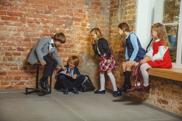 Grupo de niños que pasan tiempo juntos después de la escuela. Amigos guapos descansando después de clases antes de comenzar a hacer los deberes. Interior de loft moderno. Horario escolar, amistad, educación, concepto de unión.